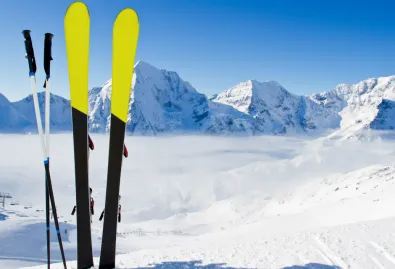 narty oraz kilki wbite w śnieg na stoku narciarskim 